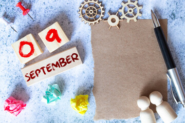 September 9. Date of September month. Number Cube with a flower and notebook on Diamond wood table for the background