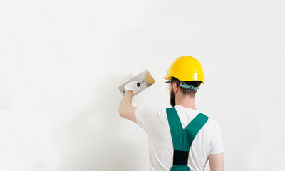 Back view of Caucasian worker with helmet, plastering wall, copy space