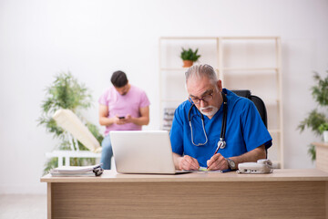Obraz premium Young male patient visiting old male doctor