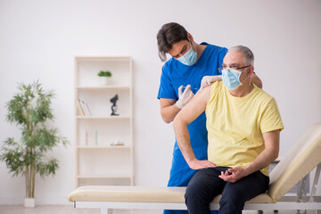 Obraz premium Old male patient visting young male doctor in vaccination concep