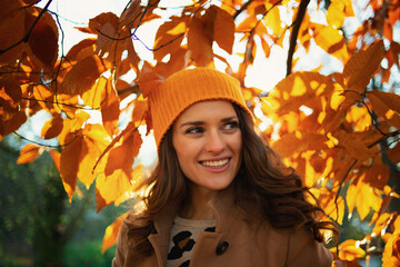 smiling modern female in brown coat and yellow hat