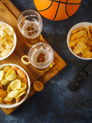 Chips, onion rings, snacks, beer in two glasses and a remote control. Dark blue background. View from above. Watching your favorite TV shows with friends, an evening with your family watching TV.