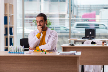 Young male chemist in drug synthesis concept