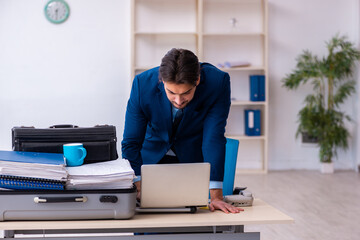 Young male employee preparing for business trip at workplace