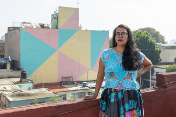 portrait of a mexican young woman wearing tehuana clothes, reading and smiling