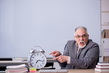 Old male teacher in front of whiteboard in time management conce