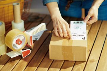 Woman applying shipping label to parcel in office