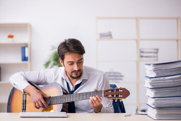 Young male employee playing guitar at workplace