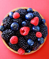 Healthy eating, food and diet concept. Blackberries,raspberries,blueberries on a bowl. Healthy breakfast. Red backgound.