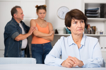 Adult woman is upseting and her husband with daughter are sympathying with her at home.