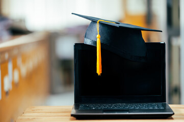 black graduation cap with yellow tassels put on laptop