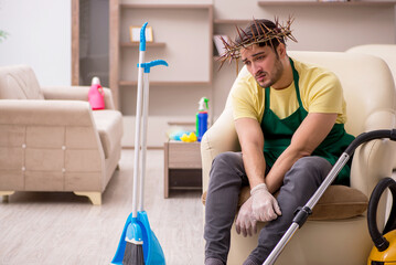 Young male contractor wearing prickly wreath on head cleaning th