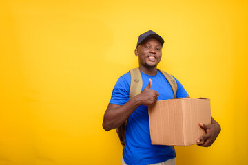 An African dispatch man doing thumbs up, carrying boxes on his shoulder and wearing a face cap