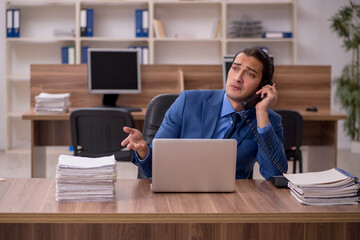 Young male employee and a lot of work in the office