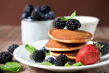 Pancakes for breakfast with blackberries and strawberries. Fluffy and delicious buttermilk pancakes.