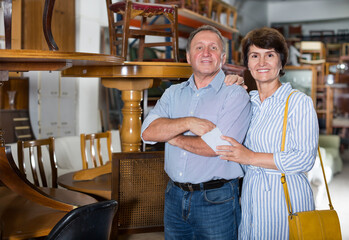 Fototapeta na wymiar Mature man and his wife are choosing furniture in a antique shop. Focus on both persons