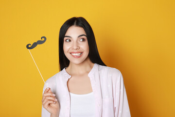 Emotional woman with fake mustache on yellow background