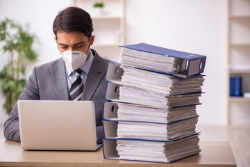 Young male employee working at workplace during pandemic
