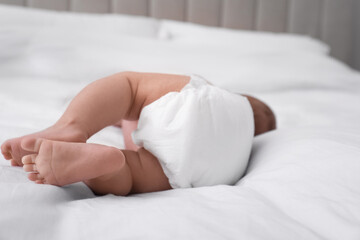 Little baby in diaper on bed, closeup