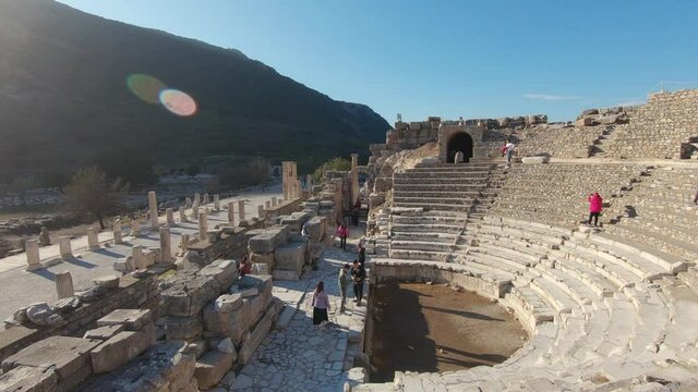 Pan right shot, tourists visiting Odeon semi circular amphitheater in Ephesus, bright sun flare.