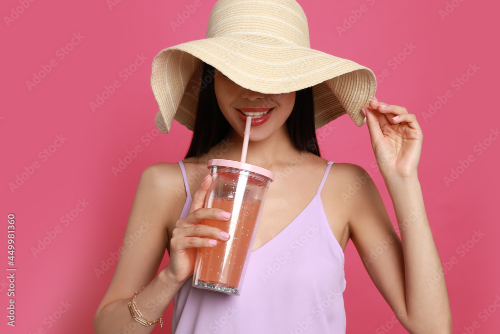 Sticker Beautiful young woman with straw hat and glass of refreshing drink on pink background