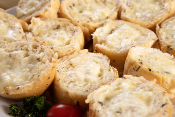 Garlic bread in white square plate on the table with cheese, rosemary, olives and cherry tomatoes.