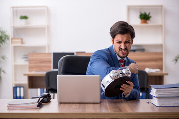 Young male employee in time management concept at workplace