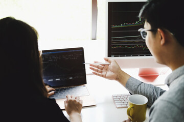 An investment expert points a pen at a computer monitor to analyze the stock market to teach you...