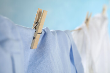 Washing line with wooden clothespin and garment against blurred background, closeup