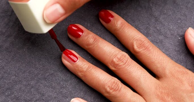 Woman Painting Her Nails with Red Nail Polish. Overhead Shot.