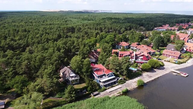 Beautiful town of Pervalka surrounded by dense pine forest on sunny day, aerial drone view