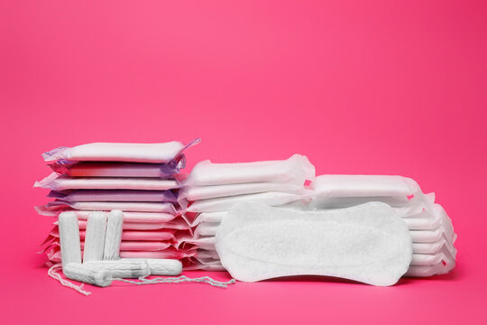 Many menstrual pads and tampons on pink background