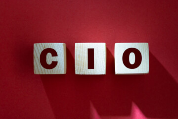 CIO written on wooden cubes - arranged in a vertical pyramid, red background, CIO - short for Chief Information Investment Officer, business concept