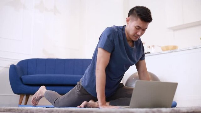 Fitness coach teaching yoga online to group of people. Young asian man beginning yoga practice with private teacher via video conference.