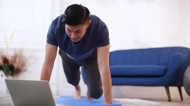 Fitness coach teaching yoga online to group of people. Young asian man beginning yoga practice with private teacher via video conference.