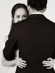 Close up of young attractive Asian woman's eyes and upper face behind man's back hugging man. Concept for pre wedding photography. In black and white