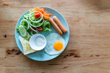 American breakfast on wood table. American breakfast with egg, sausage, bread and vegetable, Top view shot.