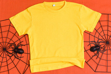 Yellow t-shirt mockup with halloween spiderweb decor on orange halloween background