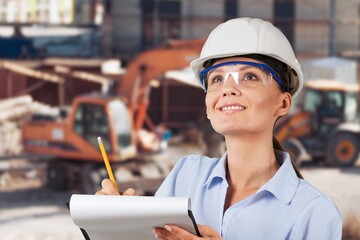 Portrait of the female engineer in hard helmet making notes