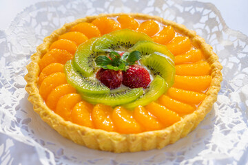 Fruit pie with fresh orange, kiwi, strawberries and cream close up on the table