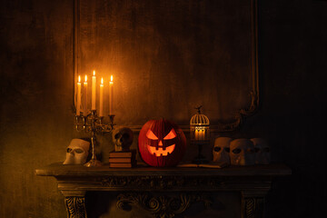 Scary laughing pumpkin and old skull on ancient gothic fireplace. Halloween, witchcraft and magic.