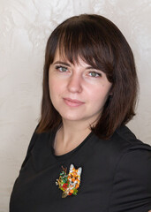 Portrait of a young woman with a handmade brooch on a light background. Facial expression, selective focus, beautiful people.