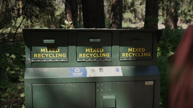 This panning video shows a row of green metal, bear proof camping trash and recycling receptacles.