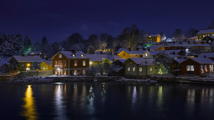Winter evening in old Porvoo with colorful blurred reflections of historic wooden houses in the water. 