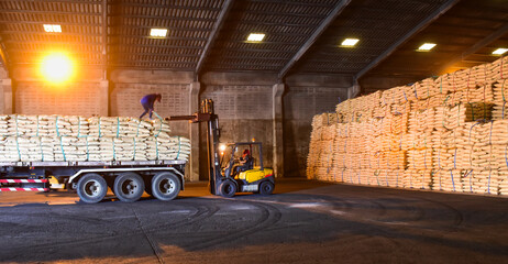 Warehouse intake,  forklift lift-off sugar bags from truck to stack inside a warehouse. Sugar,...