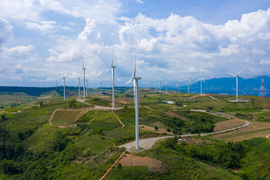 Aerial view of windmills rotating by the force of the wind for generating clean renewable energy for sustainable development in a green ecologic way on beautiful cloudy sky at highland.