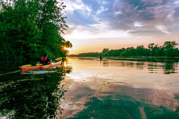 Sea kayakers paddle into the setting sun  on Long Pond on the Toronto Islands on a summer evening.