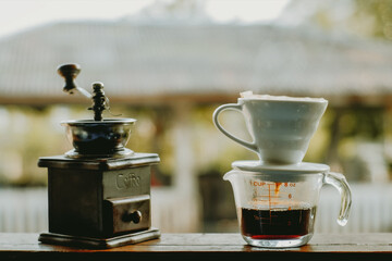 Drip brewing coffee with smoke and coffee grinder on wooden bar in morning, Drip brewing coffee concept.	