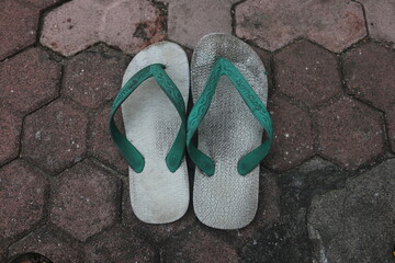 worn-looking sandals on the floor of the paving block yard