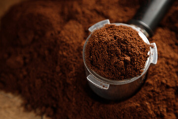 Black ground coffee in coffee holder on coffee background with texture